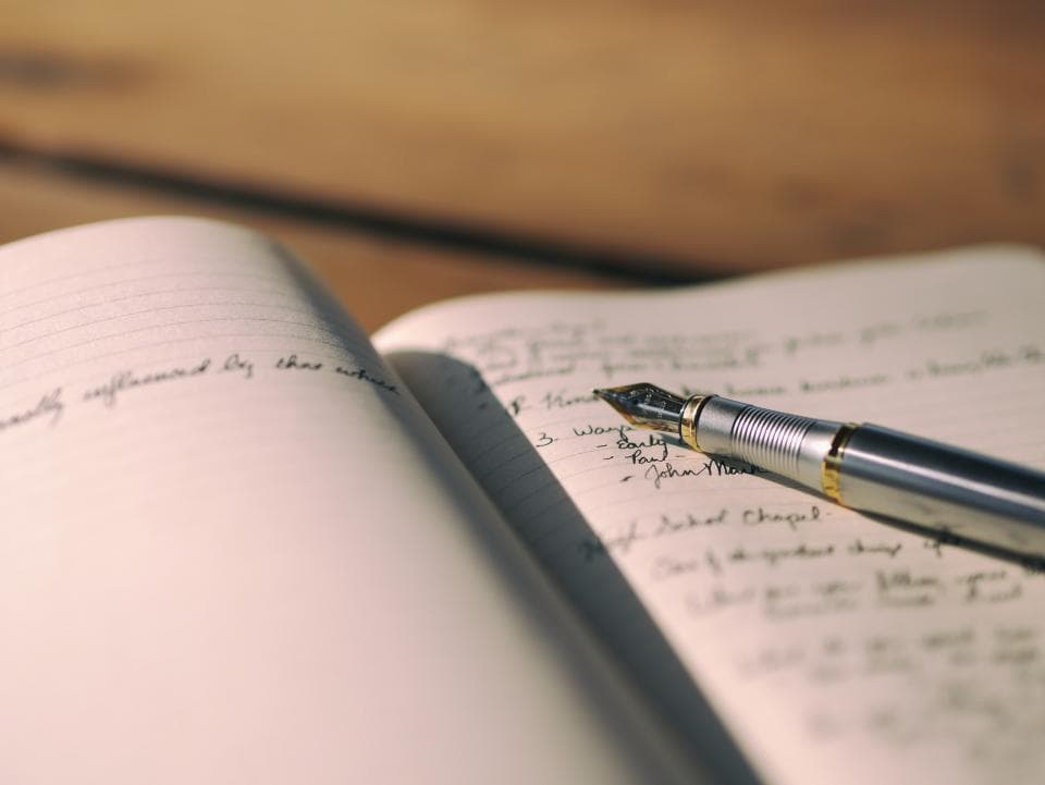A fountain pen resting on an open handwritten journal