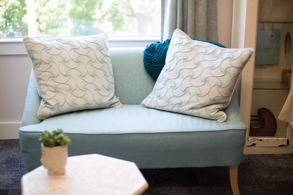 A quiet sitting room with a soft blue loveseat and pillows